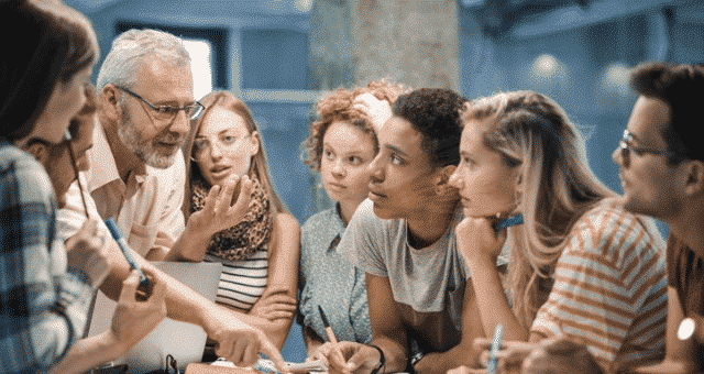 Teacher explains concept in huddle of students